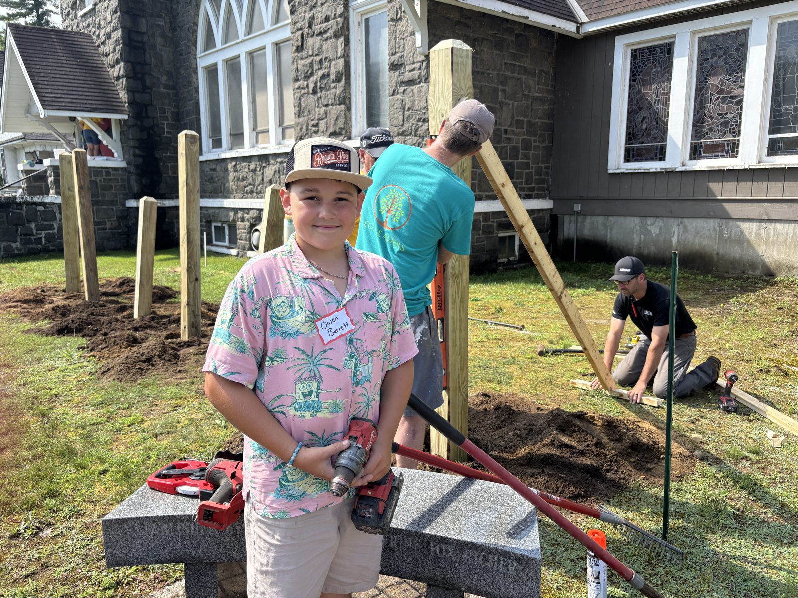 A Tupper Lake student setting fence posts alongside local tradespeople